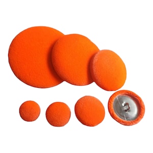 May include: Assortment of six orange velvet buttons in various sizes. The largest button is approximately 5 cm in diameter. The smallest button is approximately 2.5 cm in diameter.