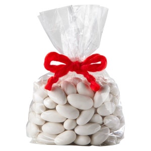 Op de afbeelding: Een doorzichtige plastic zak gevuld met witte amandelvormige snoepjes, vastgebonden met een rood lint.