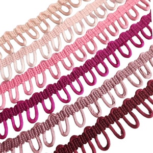 May include: A close-up of five different shades of pink and burgundy trim with a scalloped edge. The trim is made of a soft, woven fabric and has a delicate, feminine look.