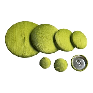 May include: Set of six lime green fabric covered buttons. The buttons are round and come in various sizes. The largest button is about 3 inches in diameter.