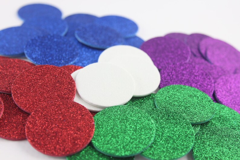 May include: A collection of colorful, glittery, circular confetti in shades of red, blue, green, purple, and white. The confetti is scattered, creating a festive and decorative appearance, suitable for various craft projects and celebrations.