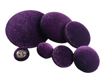 May include: A set of six purple velvet buttons of varying sizes. The buttons are round and have a smooth, velvety texture.