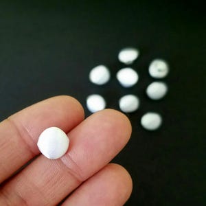 May include: A close-up of a white satin button, with several other white satin buttons in the background.