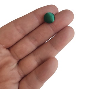 May include: A single, round, dark green button made of fabric.