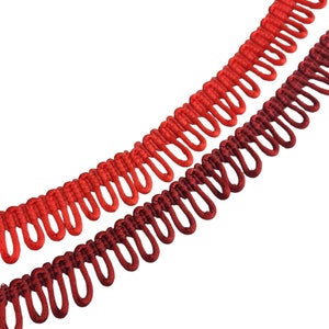 May include: Two strands of red and burgundy trim with a looped design. The trim is made of a soft, woven fabric.