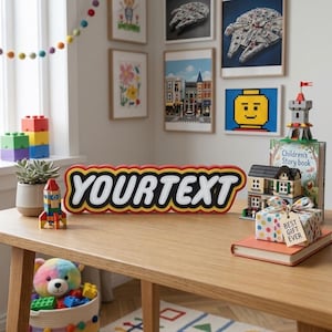 May include: A custom sign featuring the text YOURTEXT in a bold, white, blocky font with a black outline and a red border, styled like a building block logo. The sign sits on a wooden table surrounded by various colorful building block toys.