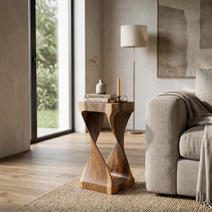 May include: A brown wooden side table with a twisted hourglass shape. The table surface holds two stacked books, a small light-coloured ceramic vase containing a dried plant stem, and a single yellow candle in a small metallic candle holder.
