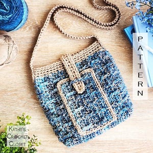 May include: A handmade crochet shoulder bag in shades of blue and beige. The bag features a flap closure and a long strap. The design includes a matching phone pocket. The text "PATTERN" is visible on a book in the background. The bag is made with a textured stitch.