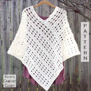 Könnte beinhalten: Cremefarbener Häkelponcho mit V-Ausschnitt, an einem Holzbügel aufgehängt. Der Poncho hat ein offenes, rautenförmiges Muster. Das Wort "PATTERN" ist rechts zu sehen, und "Kathy's Crochet Closet" links.