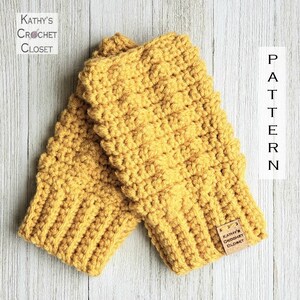 May include: A pair of mustard yellow crocheted fingerless gloves with a brown leather tag that reads "Kathy's Crochet Closet".