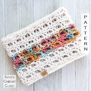 May include: A crocheted cowl with a white base and a colorful stripe of orange, pink, and blue yarn. The cowl is made with a simple stitch pattern and has a textured look. The tag on the cowl reads "Kathy's Crochet Closet".