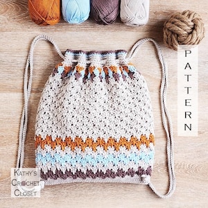May include: A crochet drawstring backpack featuring a beige base with horizontal stripes in orange, light blue, and dark brown. The bag has matching beige cord straps and a cinched top closure. The text "Kathy's Crochet Closet" and "PATTERN" are visible.