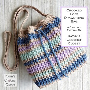 Pu&ograve; includere: Borsa a cordoncino all'uncinetto con un motivo a righe in tonalit&agrave; di blu, viola, verde e marrone. La borsa ha una tracolla lunga ed &egrave; realizzata con un punto all'uncinetto. Il testo "CROOKED POST DRAWSTRING BAG A CROCHET PATTERN BY KATHY'S CROCHET CLOSET" &egrave; in un riquadro viola sul lato destro dell'immagine.