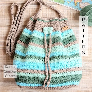 May include: A crocheted drawstring bag with a brown strap. The bag is made with a striped pattern of brown, green, and blue yarn. The bag has a wooden tag with the letters "KCG" on it.