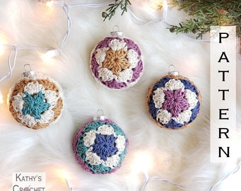 May include: Four crocheted Christmas ornaments in different color combinations of teal, purple, cream, and brown. The ornaments are displayed on a white fluffy surface with a string of white lights.