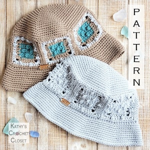 May include: Two crocheted bucket hats, one in beige with teal and white squares and the other in light gray. Both hats have a leather label with the text "KCC" on them. The hats are on a wooden surface with sea glass and the text "PATTERN" in large letters.