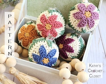 May include: Five crocheted ornaments in a box with wooden beads. The ornaments are in the shape of a flower with different colored petals. The colors are purple, pink, blue, orange, and green.