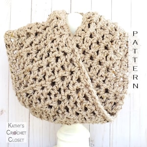 May include: A crocheted cowl in a beige color, made with a chunky yarn. The cowl is displayed on a white mannequin against a white wood background. The text "PATTERN" is written vertically on the right side of the image.