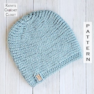 May include: A light blue crocheted beanie hat with a brown leather tag that says "KCC".