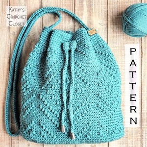 May include: Teal crochet drawstring bag with a long strap. The bag has a textured stitch pattern and is made with a soft yarn. The bag is on a wooden background with a ball of yarn.
