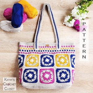 May include: A crochet tote bag featuring a granny square pattern in blue, yellow, white, and magenta. The bag has two long shoulder straps and a small rectangular tag. The text "PATTERN" and "Kathy's Crochet Closet" are visible in the image.