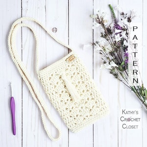 May include: A white crocheted crossbody bag with a tassel. The bag has a wooden tag that says "KCC".