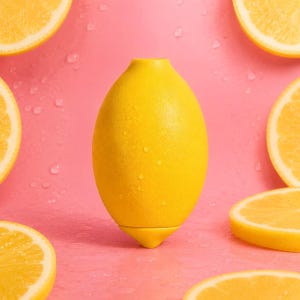 Peut inclure: Un presse-agrumes jaune vif en forme de citron centré sur un fond rose. L'objet présente un corps lisse et arrondi avec une petite base pointue et une ouverture supérieure. Plusieurs tranches de citron frais sont disposées autour de l'objet.