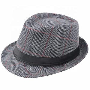 Op de afbeelding: Een fedora hoed met een grijs en zwart glen plaid patroon met dunne rode accentlijnen. De hoed is voorzien van een effen zwarte stoffen band rond de basis van de kroon, een gestructureerde rand en een ingeknepen bovenkant kenmerkend voor deze stijl.