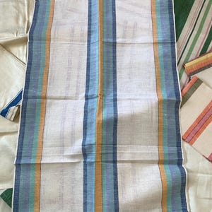 May include: A collection of white linen towels with vertical stripes in various colors. The central towel features stripes of blue, teal, and orange. Other towels display stripes of red, green, and pink. The towels are folded and arranged on a white surface.