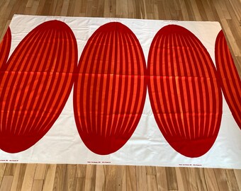 May include: A rectangular piece of white fabric featuring a repeating pattern of large, vertical, oval-shaped motifs in shades of bright red and orange. Each oval contains thin, vertical stripes of alternating red and orange tones.