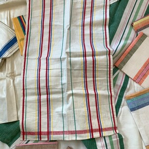 May include: White linen kitchen towels with vertical stripes in red, blue, yellow, and green. Several other striped towels are visible, with various stripe colors and patterns. The towels are likely for kitchen or home use.
