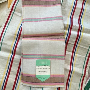 May include: White linen and cotton blend hand towel with pink, brown, and green stripes. The towel has a tag that reads "App. Size 16" x 16", Grandeur App. 41 x 41 cm, Linen 51%, Cotton 49%" and "Made in Poland, Fabrique en Pologne, CA 00027."