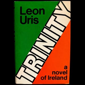 May include: A hardcover book titled Trinity by Leon Uris, a novel of Ireland. The cover features a diagonal design with a green section on the left, an orange section on the right, and the word TRINITY printed in large white letters across the center.