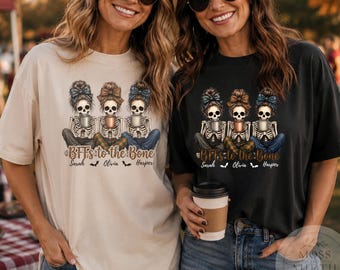 May include: Two t-shirts, one beige and one black, each featuring a graphic of three skeletons with messy buns and headbands holding mugs. The text reads "BFFs to the Bone" with the names "Sarah", "Olivia", and "Harper" printed below.