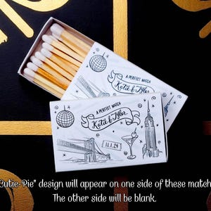 May include: Matchbox with a white box and a black and white illustration of a disco ball, the Brooklyn Bridge, a cocktail, and the Empire State Building. The text reads "A Perfect Match Katie & Tyler" and "11.1.24".