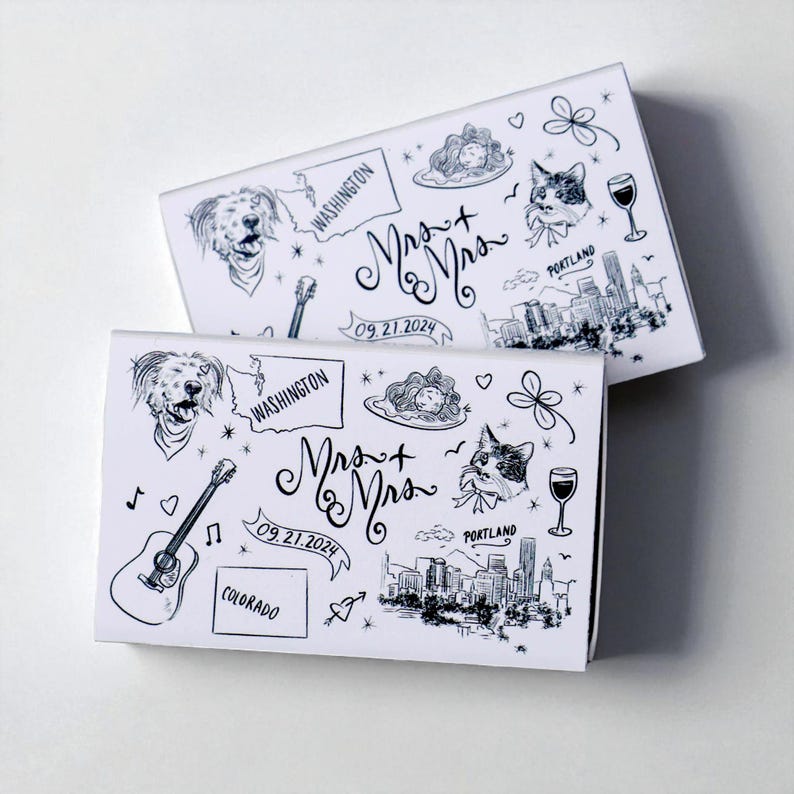 May include: Two white boxes with black line art illustrations. The boxes feature drawings of a dog, a cat, a guitar, and a cityscape. The text "Mrs. + Mrs." and the date "09.21.2024" are also present. The boxes are likely for a wedding.