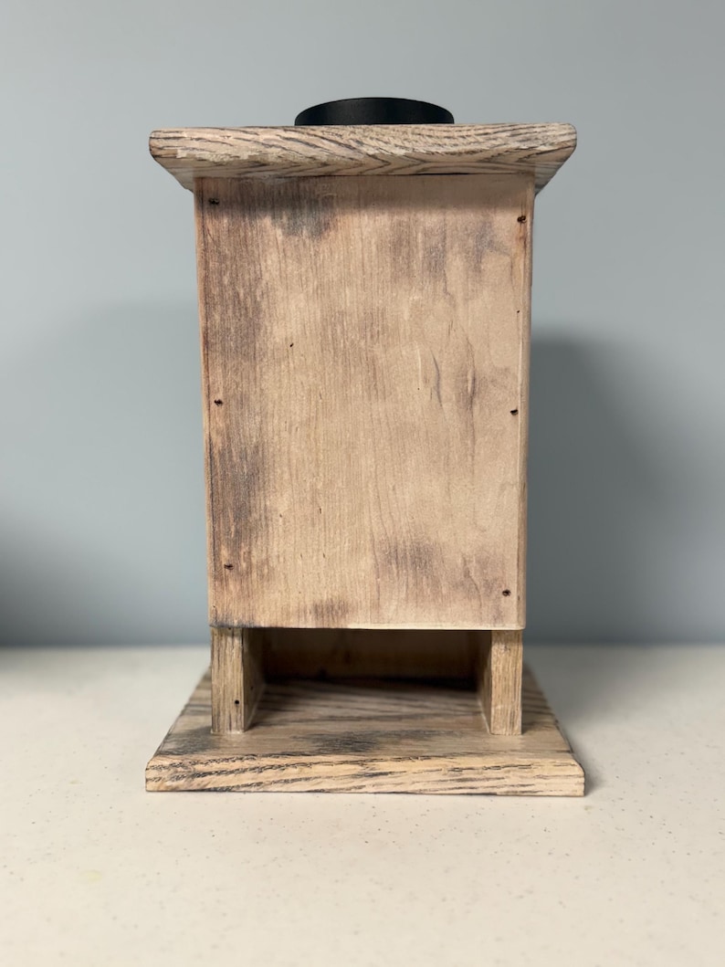 May include: A rustic wooden box with a distressed finish. The box has a small opening on the front and a black top.