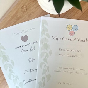 Op de afbeelding: Twee witte vellen papier met lichtgroene bladillustraties aan de linkerkant. Het linkerblad bevat de tekst Mijn diploma, Ik ben trots op mezelf, Naam Kind, Datum, Handtekening, Berichte van. Het rechterblad bevat de tekst Mijn Gevoel Vandaag, Emotieplanner voor Kinderen, Leer gevoelens herkennen, begrijpen en bespreekbaar maken, Nûr & Papers.