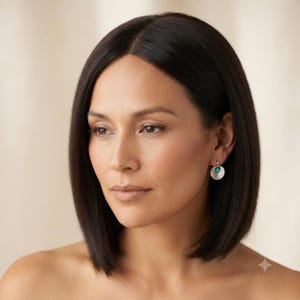 May include: A pair of silver-toned drop earrings featuring a circular, textured metal disc with a small, round, bright turquoise stone set in the center. The earrings hang from a simple metal hoop, providing a subtle and reflective metallic finish.