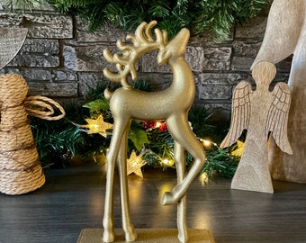 May include: Gold glitter reindeer stocking holder. The reindeer is standing on a gold glitter base with a hook on the bottom.