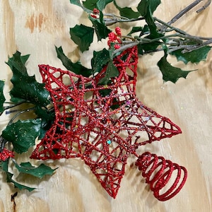 May include: Red sparkly star-shaped Christmas tree topper with a red spiral base.