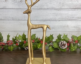 May include: Gold metal reindeer stocking holder with a hook on the bottom. The reindeer is standing on a gold base.