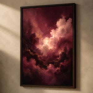 Op de afbeelding: Een ingelijst kunstwerk aan de muur met een dramatische, schilderachtige weergave van een stormachtige lucht vol dieprode, bordeauxrode en donkerrode wolken. Een helder, warm licht schijnt vanuit het midden van de wolkenformatie.