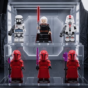May include: Six plastic minifigures arranged on a two-tiered clear display stand. The top row features a white trooper, a figure with white hair and a red lightsaber, and a white trooper. The bottom row shows three identical red armored figures.