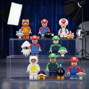 May include: A collection of eleven plastic building block figures and accessories featuring characters from the Super Mario franchise, including Mario, Luigi, and Toad, arranged on a three-tiered clear acrylic display stand for organization.