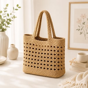 May include: A tan crochet tote bag featuring a structured rectangular base and two matching handles. The body of the bag is crafted with a repeating open-square grid pattern, while the top and bottom sections are made with a solid, tight stitch.
