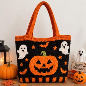 May include: A black and orange crochet tote bag featuring a large central jack-o'-lantern, two white ghosts, orange bats, and small orange stars. The bag has two sturdy handles and a striped orange and black pattern along the bottom edge.