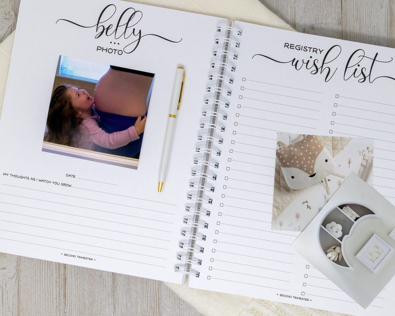 May include: A white and black pregnancy journal with a photo of a pregnant woman and a child. The journal has a section for "belly photo" and a section for "registry wish list".