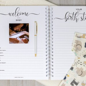 May include: A white baby journal with a spiral binding. The front cover has the words "welcome baby" in cursive script and a photo of a baby being held by a person. The back cover has the words "your birth story" in cursive script and a baby onesie with a colorful animal print.