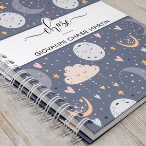 Puede incluir: Un cuaderno gris de espiral con un patr&oacute;n de luna y estrellas. La portada tiene el nombre "chase" escrito en cursiva y el texto "GIOVANNI CHASE MARTIN".